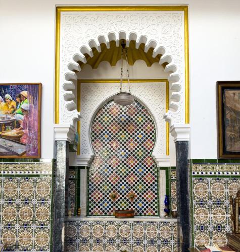 a mosaic wall in a building with paintings on it at Riad Dar Achaach in Tetouan
