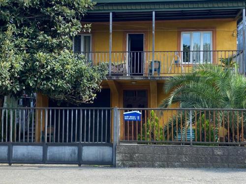 a yellow house with a fence in front of it at Mака и Сулико in Batumi
