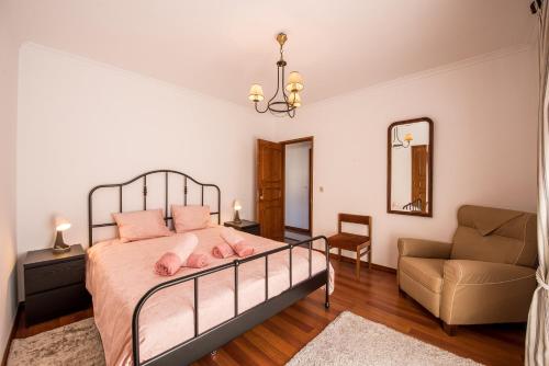 a bedroom with a bed and a chair and a mirror at Cantinho alegre em Cascais in Cascais