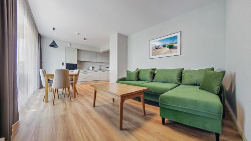 a living room with a green couch and a table at Apartamenty Helski Brzeg in Hel