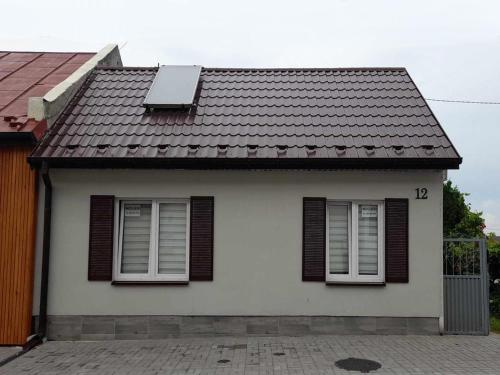 a white house with brown windows and a roof at Noclegi Przy Niemczówce in Chęciny