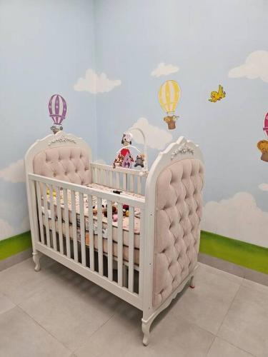 una culla nella stanza di un bambino con nuvole e palloncini di Casa Ideal e Confortável a Sinop