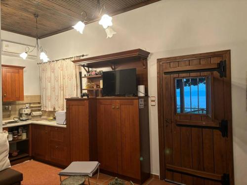 una cucina con mobili in legno e una TV su una porta di Οξυγόνο Πέτρινο εξοχικό στη Βυζίτσα Πηλίου a Vizitsa