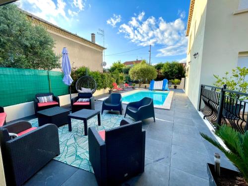 une terrasse avec une piscine, des chaises, une table et un parasol dans l'établissement Grande maison de vacances, à Alès