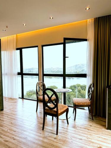 a room with a table and chairs and windows at Hotel Iliria in Shkodër
