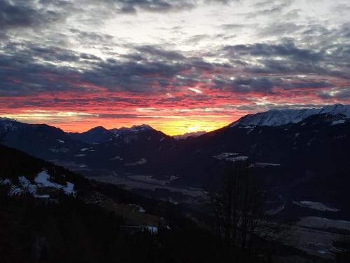 a sunset over a mountain range with snow covered mountains at Almen-Kräuter-Oberreiter in Dellach im Drautal
