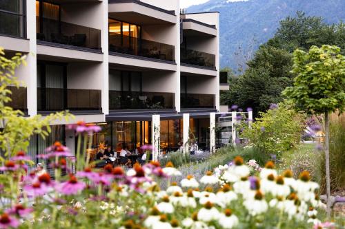 a building with a garden with flowers in front of it at Boutique Hotel AMARIL in Castelbello-ciardes