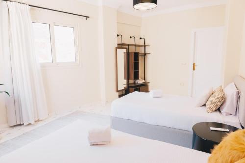 a white bedroom with two beds and a window at VIDA by Elegant Hospitality in Cairo