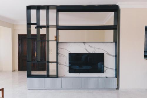 a living room with a tv and a marble wall at VIDA by Elegant Hospitality in Cairo