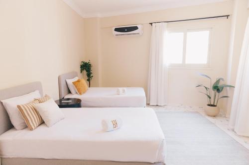 two beds in a room with a couch and a window at VIDA by Elegant Hospitality in Cairo