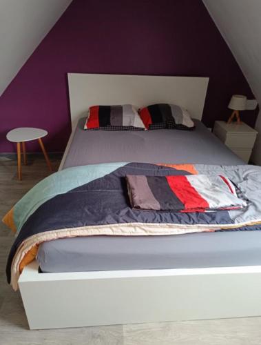 a bedroom with a bed with a purple wall at Ancienne maison de pêcheur atypique in Quillebeuf-sur-Seine