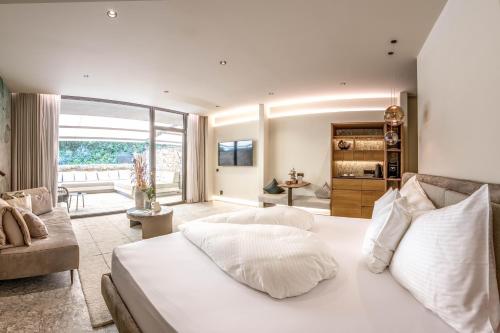 a bedroom with a large white bed and a living room at Boutique Hotel AMARIL in Castelbello-ciardes