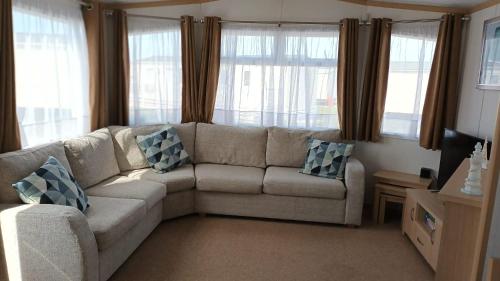 a living room with a couch and windows at Carnaby Holiday Caravan, West Sands, Selsey in Selsey