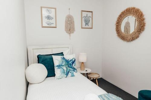 a bedroom with a bed with blue pillows and a mirror at 'Admirals' Coastal Haven - 200mtrs from Beach in Mooloolaba