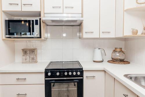 a white kitchen with a stove and a microwave at 'Admirals' Coastal Haven - 200mtrs from Beach in Mooloolaba