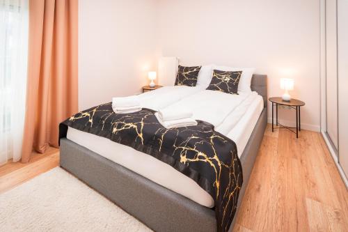 a bedroom with a large bed with white and gold sheets at Warmiński Port by RENT4YOU in Olsztyn