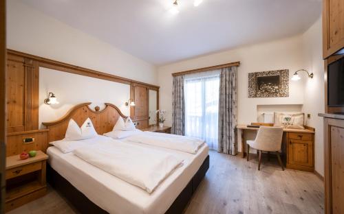 a hotel room with a large bed and a desk at Wellness Hotel Gran Risa***S in La Villa