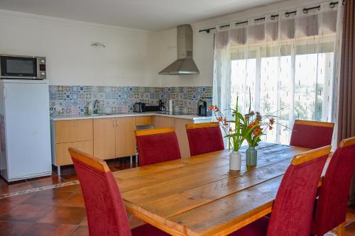a kitchen with a wooden table and red chairs at Villa Casa da Rosa, com piscina privada in Carvalheira Grande