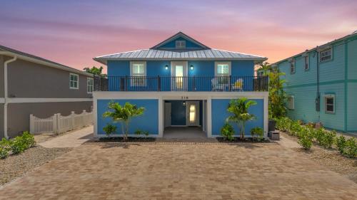una casa azul con balcón y palmeras en 218 Primo Dr - Dolphin Beach House home, en Fort Myers Beach