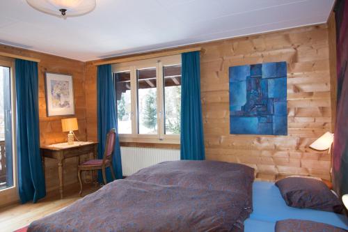 a bedroom with a bed and a desk and windows at Chalet Cresta di Saas in Saas-Fee