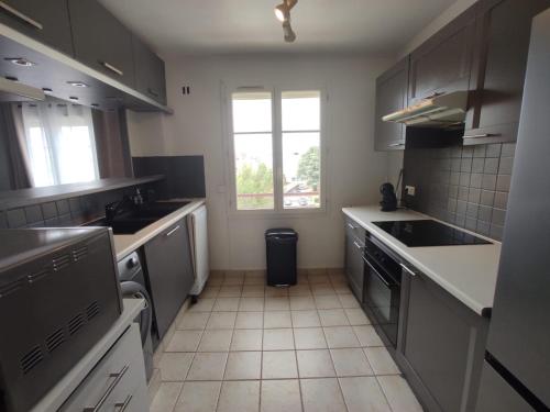 une cuisine avec des appareils électroménagers blancs et une fenêtre. dans l'établissement Cosy 2 Pièces proche Paris, à Les Pavillons-sous-Bois