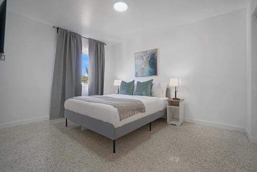 a white bedroom with a bed and a window at Elegant Wynwood Flats in Miami