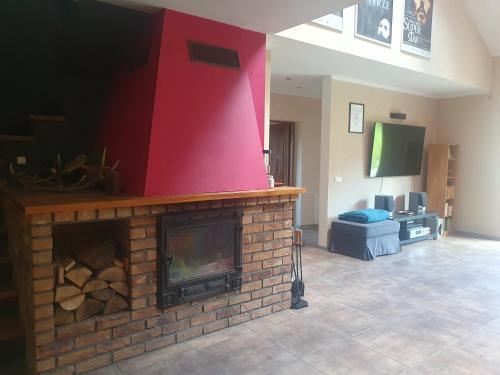 a living room with a brick fireplace with a red wall at Kuniec Świata in Błotnia
