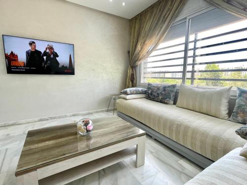 a living room with a couch and a tv on the wall at Luxueux Appartement Parc Champs de Cours avec Wifi Fibre 200 Mo in Fès