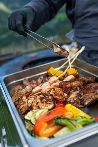a person is cooking food on a grill at Hotel-Chalet Pennhof in Barbiano