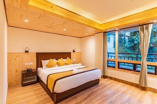 a bedroom with a large bed and a large window at The Golden Retreat Hotel in Pelling in Pelling