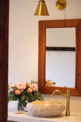 a bathroom sink with a mirror and a vase of flowers at Mukima Manor in Nanyuki