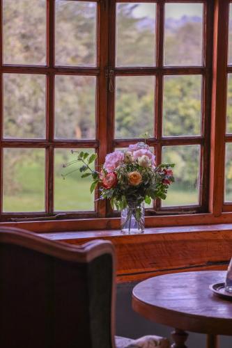 a vase of flowers sitting on a table in front of a window at Mukima Manor in Nanyuki