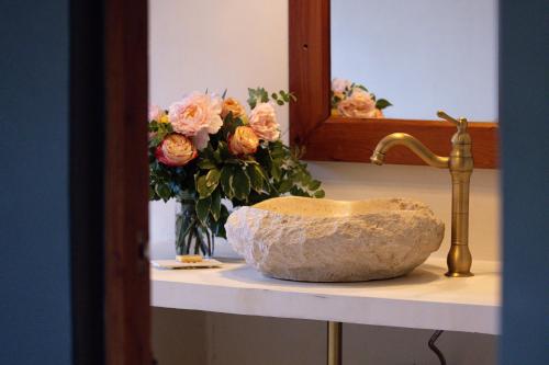 a bathroom counter with a sink and a vase of flowers at Mukima Manor in Nanyuki