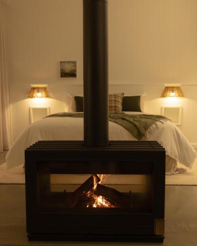 a bedroom with a fireplace in front of a bed at Edge Luxury Villas in Wilyabrup