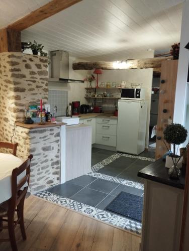 une cuisine avec un réfrigérateur blanc et un comptoir dans l'établissement Le gîte du courtil, à Tressé