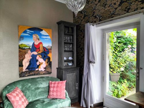 a living room with a green couch and a painting at Le Jardin Secret & Spa - Chambre d'Hôtes in Saint-Brieuc
