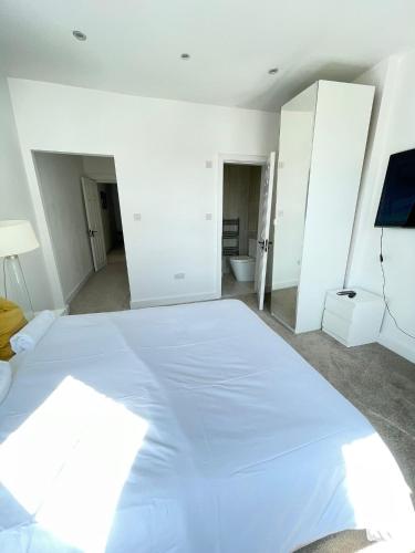 a bedroom with a large white bed and a bathroom at Stone Lodge 2 min Walk From Edgware Underground in Edgware