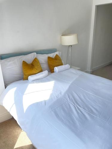 a large white bed with yellow pillows on it at Stone Lodge 2 min Walk From Edgware Underground in Edgware