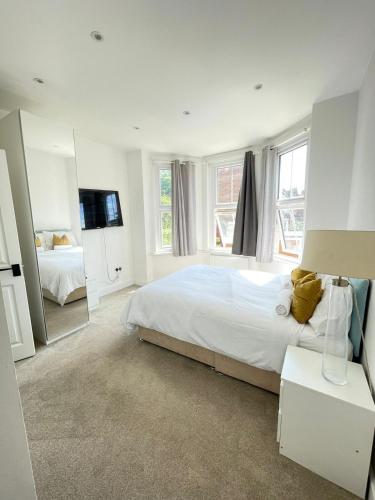 a white bedroom with a large bed and a mirror at Stone Lodge 2 min Walk From Edgware Underground in Edgware