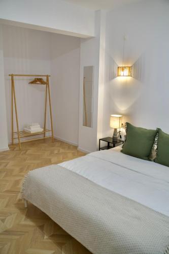 a white bedroom with a large bed with green pillows at Tzatziki Studios in Kavala