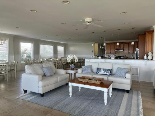 a living room with two couches and a kitchen at Most Requested 16 Br Oceanfront Home in Holden Beach in Holden Beach