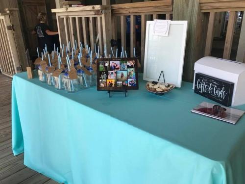a blue table with bottles of water and a refrigerator at Most Requested 16 Br Oceanfront Home in Holden Beach in Holden Beach