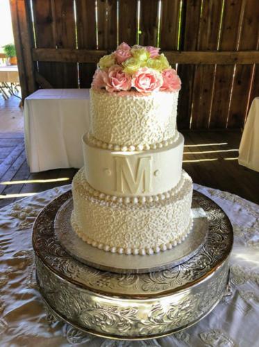 a three tiered wedding cake with pink roses on it at Most Requested 16 Br Oceanfront Home in Holden Beach in Holden Beach