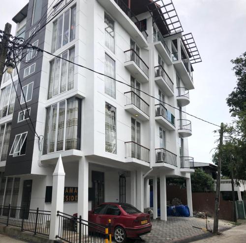 a red car parked in front of a white building at Amaze Residence luxury 2bedroom apartment 2 in Boralesgamuwa