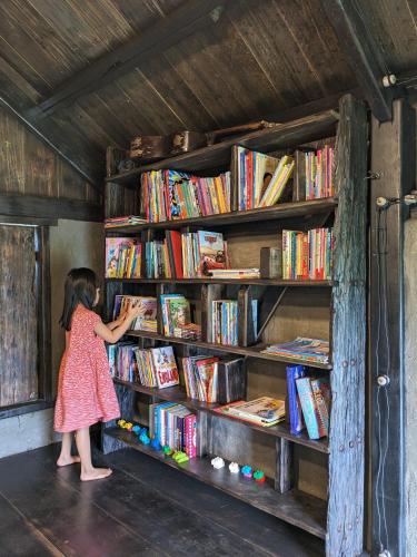 a little girl reaching for a book on a book shelf at Ivy Coffee Farm - Cabin House in Ðưc Trọng