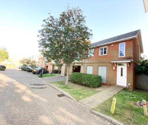 a brick house with a tree on a street at 2 Bedroom Flat near Redhill train station, easy access to Gatwick & London in Redhill