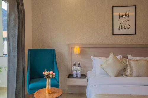 a hotel room with a bed and a blue chair at Perfectstayz Value Alpine Near Laxman Jhula in Rishīkesh