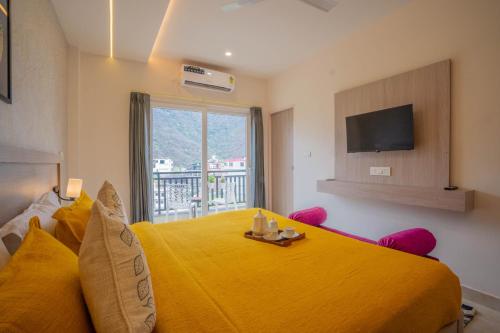 a bedroom with a large yellow bed and a television at Perfectstayz Value Alpine Near Laxman Jhula in Rishīkesh