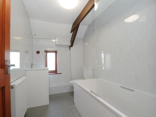 a white bathroom with a tub and a sink at West Lee in Bude