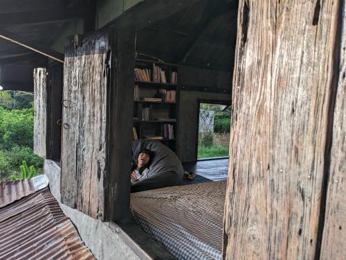 a person laying in a bed in a wooden house at Ivy Coffee Farm - Cabin House in Ðưc Trọng